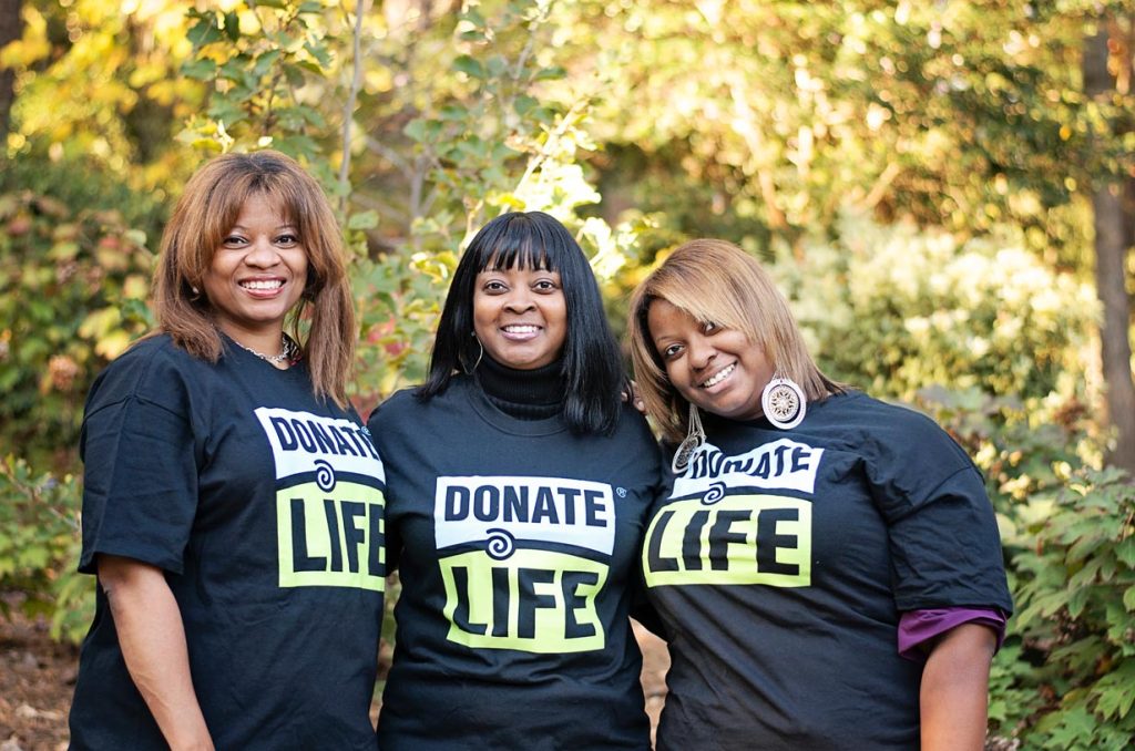 Three woman pose together while wearing donate life t-shirts outside