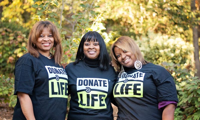 Three woman pose together while wearing donate life t-shirts outside