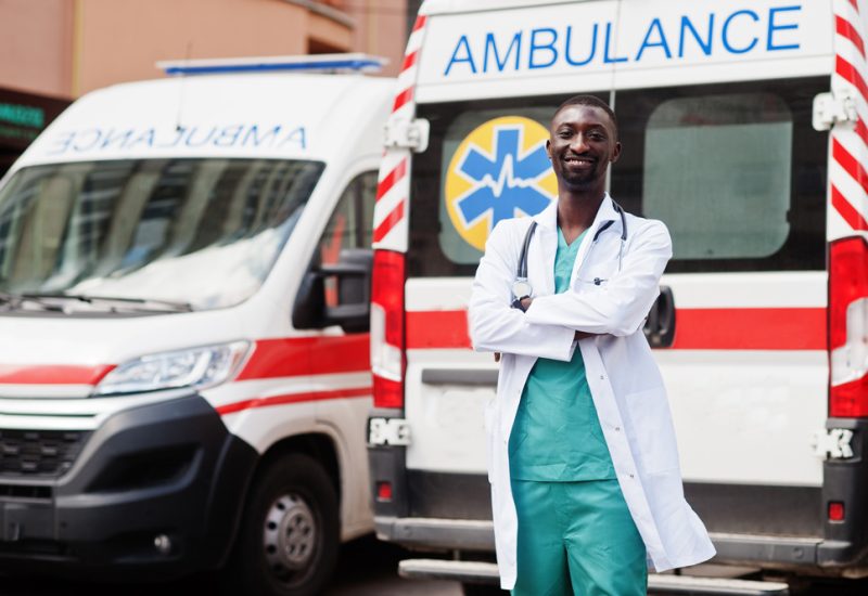 Doctor stands in front of a parked ambulance