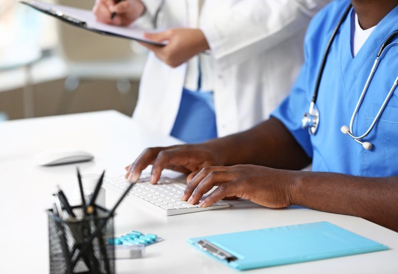 Hospital staff member, in scrubs, types on a keyboard