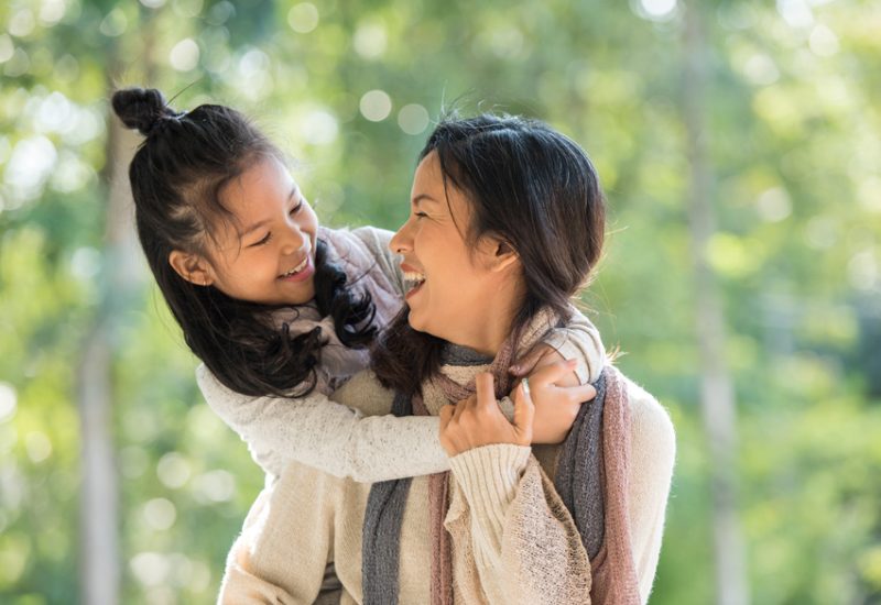 Mother and daughter laugh together as they walk in nature