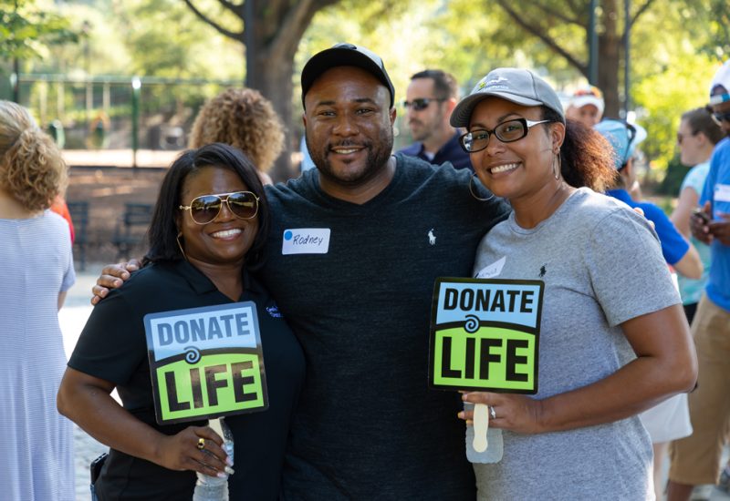 Honorbridge staff members hold donate life signs at a staff event